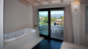 Un baño moderno con bañera, una puerta corredera de vidrio que da a un balcón con mobiliario exterior.