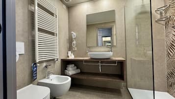Ein modernes Badezimmer mit einer Bidet-Funktion, einem Waschbecken, einem Spiegel und einer Dusche.