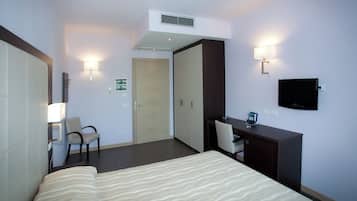 Une chambre d’hôtel équipée d’un lit, d’un bureau, d’une chaise, d’une armoire et d’un téléviseur.