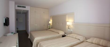 A hotel room with two beds, a desk, and a wardrobe.