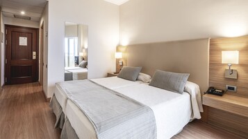 A hotel room with a large bed, bedside lamps, a nightstand with a phone, and a wooden headboard.