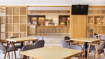Un ristorante moderno con arredamento in legno, un'area bar e un televisore a schermo piatto.