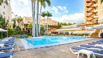 Een buitenzwembad, ligstoelen bij het zwembad