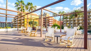 Un salón en la azotea con asientos exteriores y vistas a un hotel.