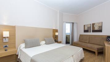 A hotel room with a large bed, a sofa, a desk, and a window with a view.