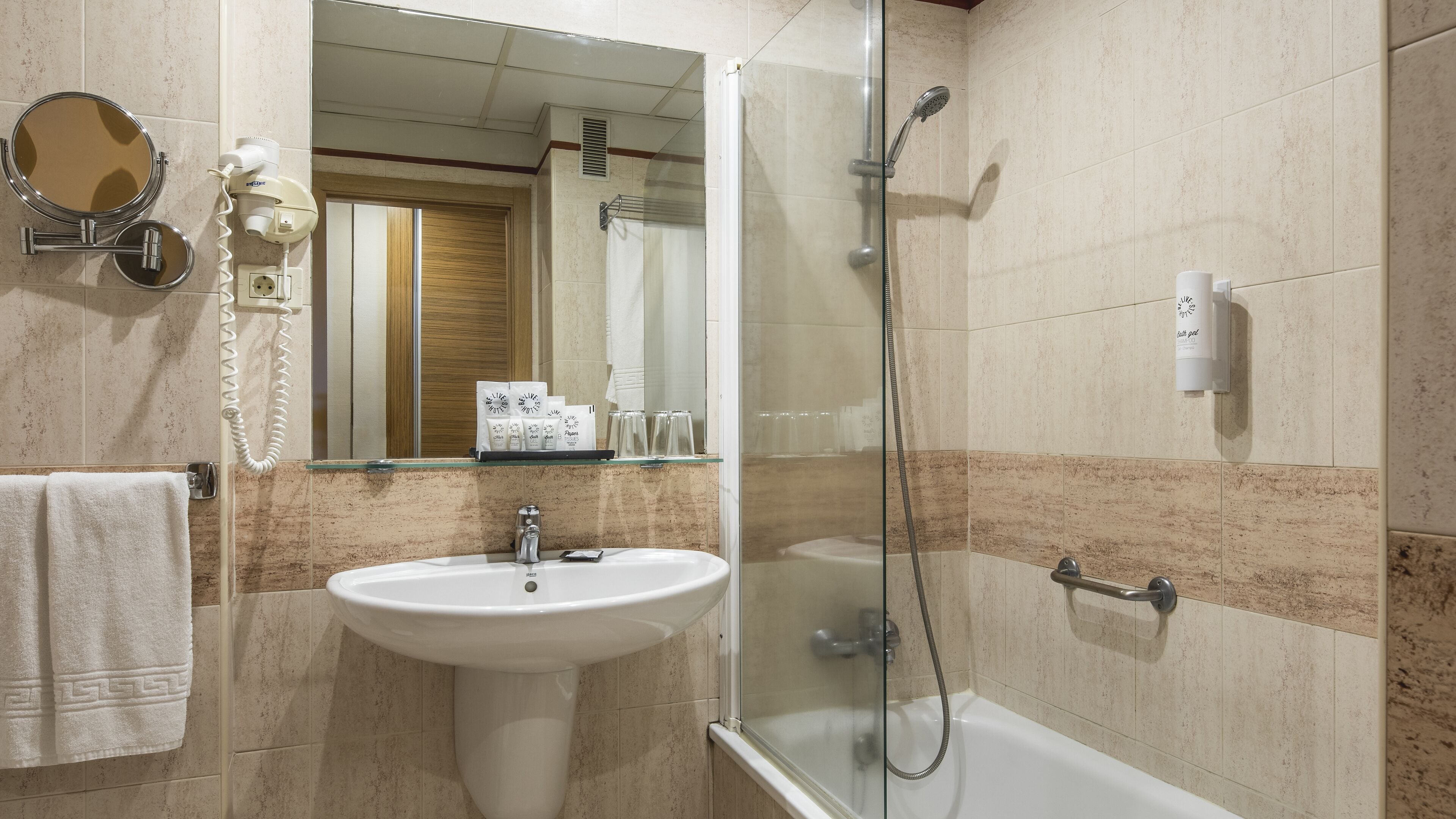 A bathroom with a sink, mirror, and shower.