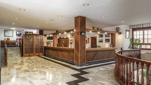 Una zona de recepción con un mostrador de madera, una recepción y un cartel indicador.