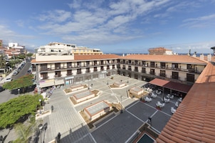 Un patio con techo de tejas, rodeado de edificios con balcones y vista al mar.