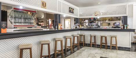 Zona de bar con mostrador, taburetes y una máquina de café.