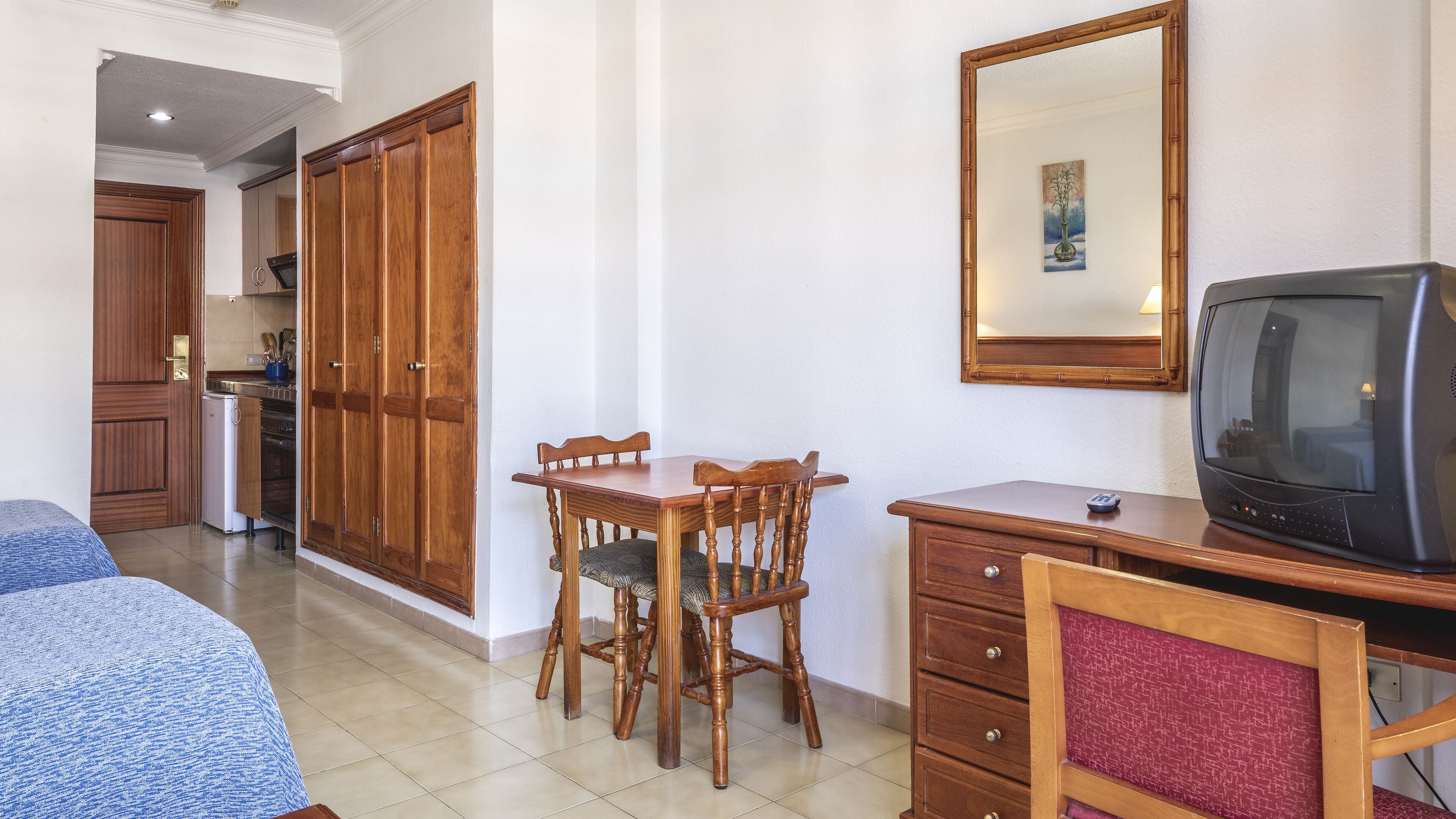 Una habitación con una mesa de comedor de madera, sillas, un televisor y un armario.