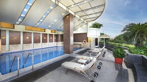 A modern indoor pool area with lounge chairs, a small pool, and a covered seating area. - The Accord Metropolitan (Chennai)