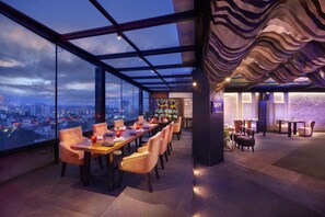 A high-rise restaurant with a panoramic city view, modern interior design, and a cozy seating area. - The Accord Metropolitan (Chennai)