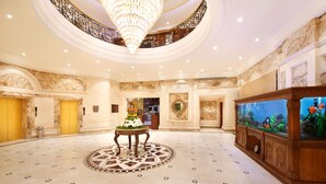 A spacious lobby with a marble floor, a large chandelier, and a decorative fish tank. - The Accord Metropolitan (Chennai)