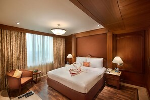 A hotel room with a large bed, two bedside tables, a chair, a desk, and a lamp. - The Accord Metropolitan (Chennai)