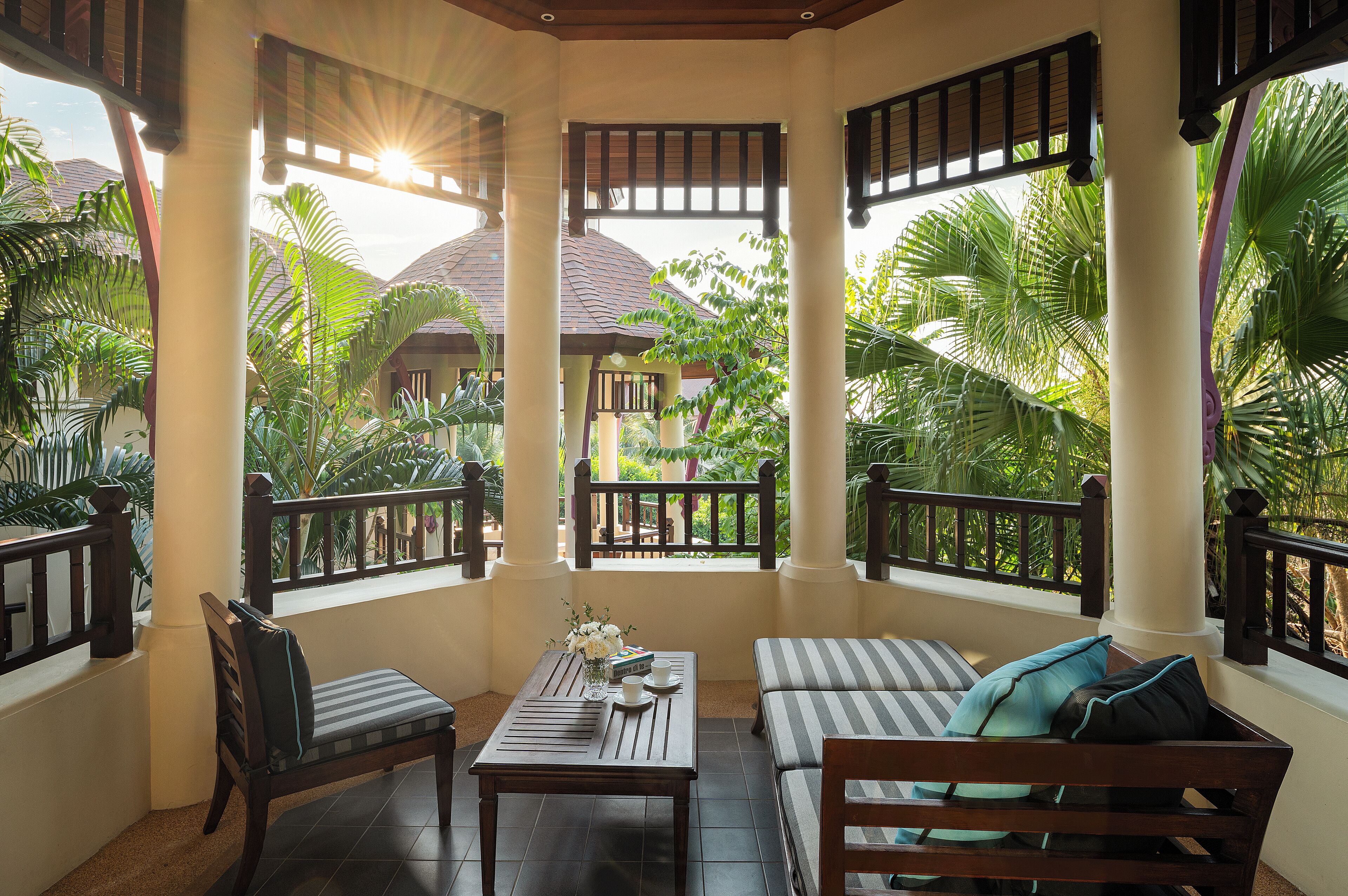 A covered outdoor seating area with a table, chairs, and a sofa.