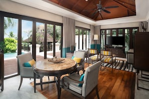 A spacious living area with a round table, comfortable seating, a TV, and a view of the outdoors.