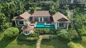 A large, two-story house with a swimming pool, surrounded by lush greenery and palm trees. - InterContinental Pattaya Resort by IHG (Pattaya)