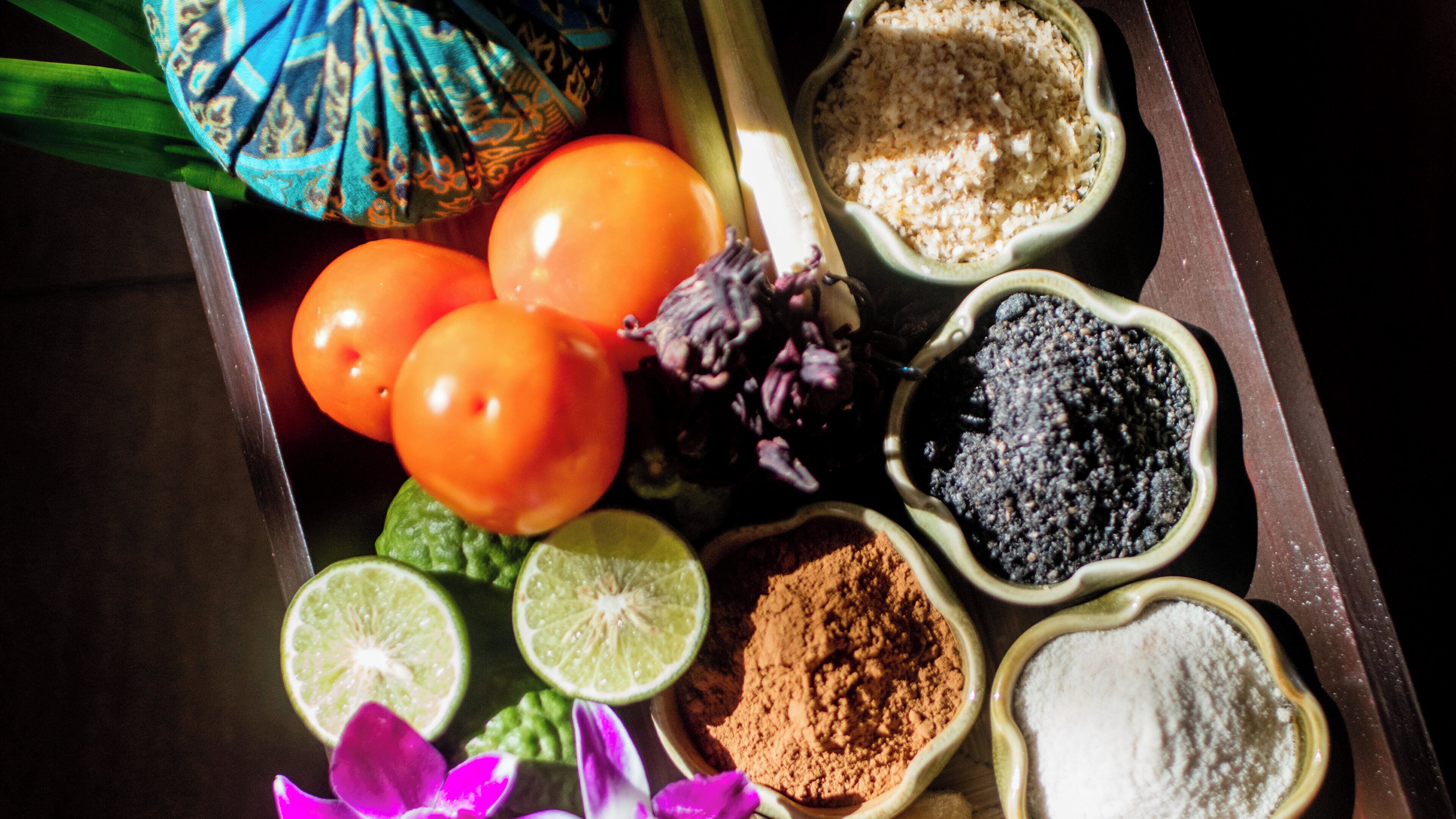 Una bandeja con diversos alimentos, incluyendo tomates, gajos de lima y especias.