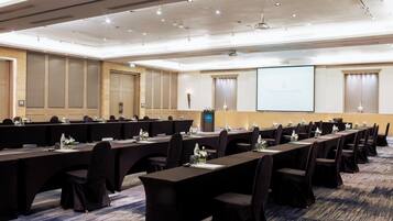 Une salle de conférence équipée de longues tables, de chaises et d’un écran de projection affichant le mot « INTERCONTINENTAL ».