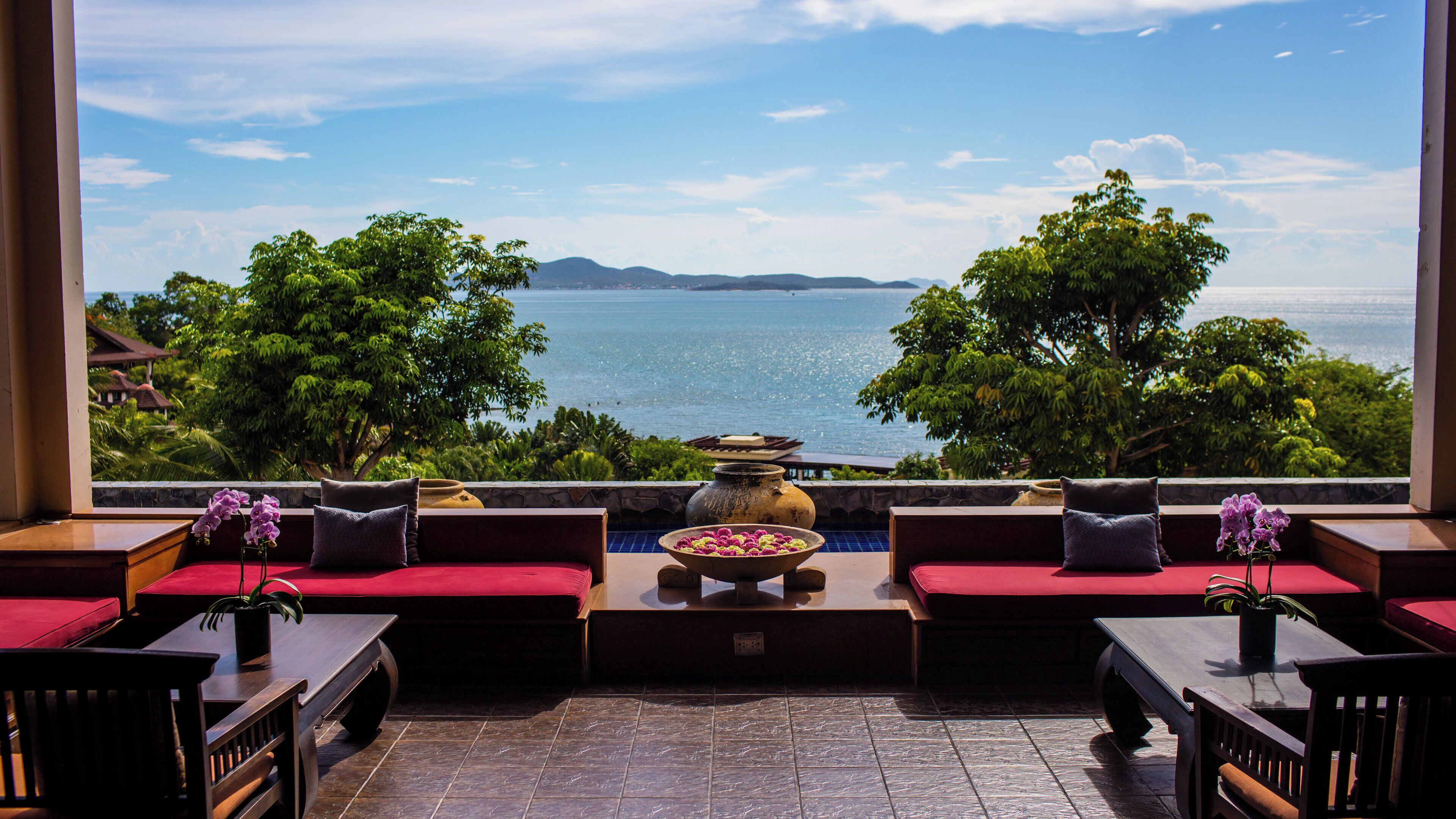 A seating area with a view of the sea, a decorative bowl, and a stone wall.