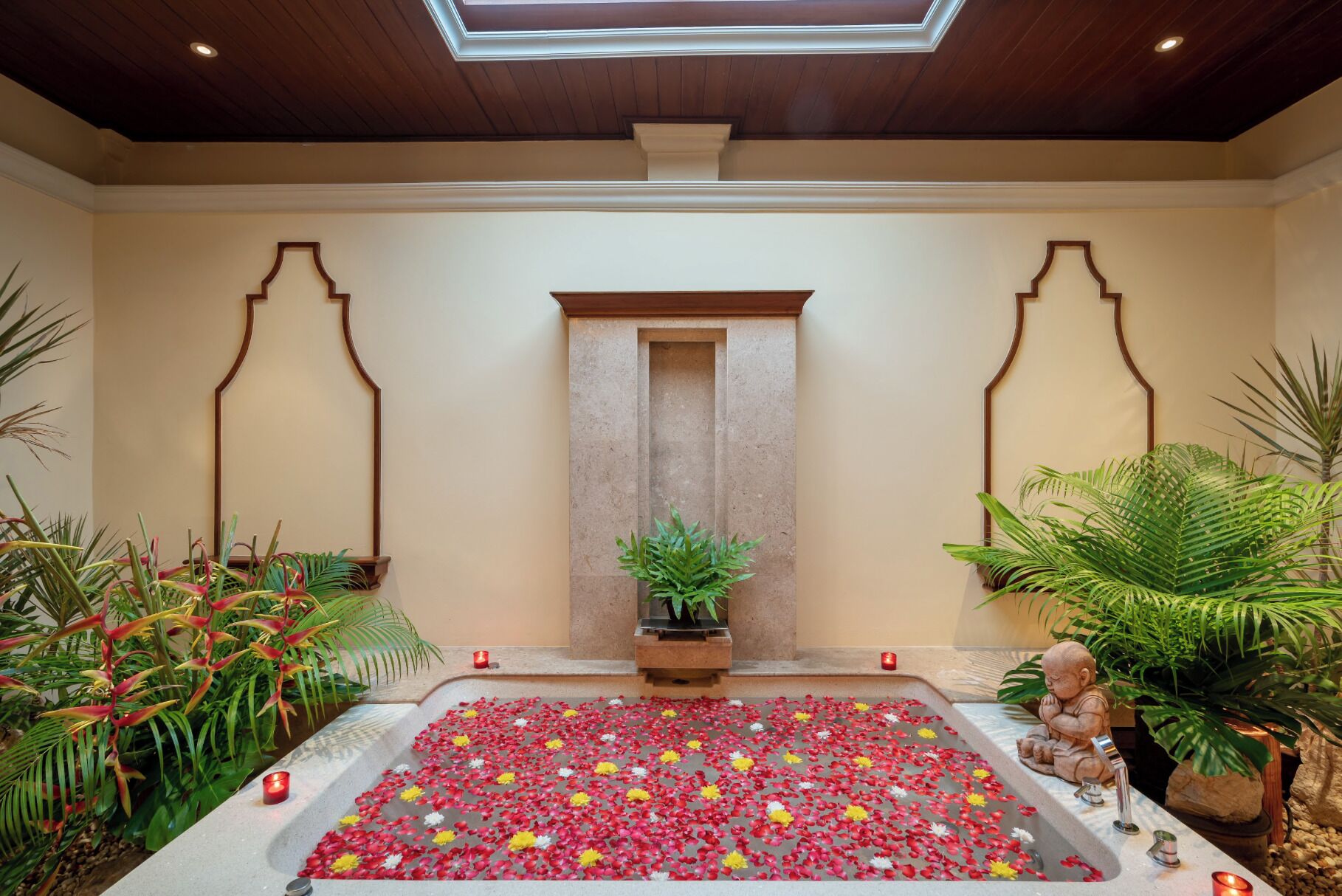 A serene indoor space with a central water feature, surrounded by lush greenery and a decorative archway.