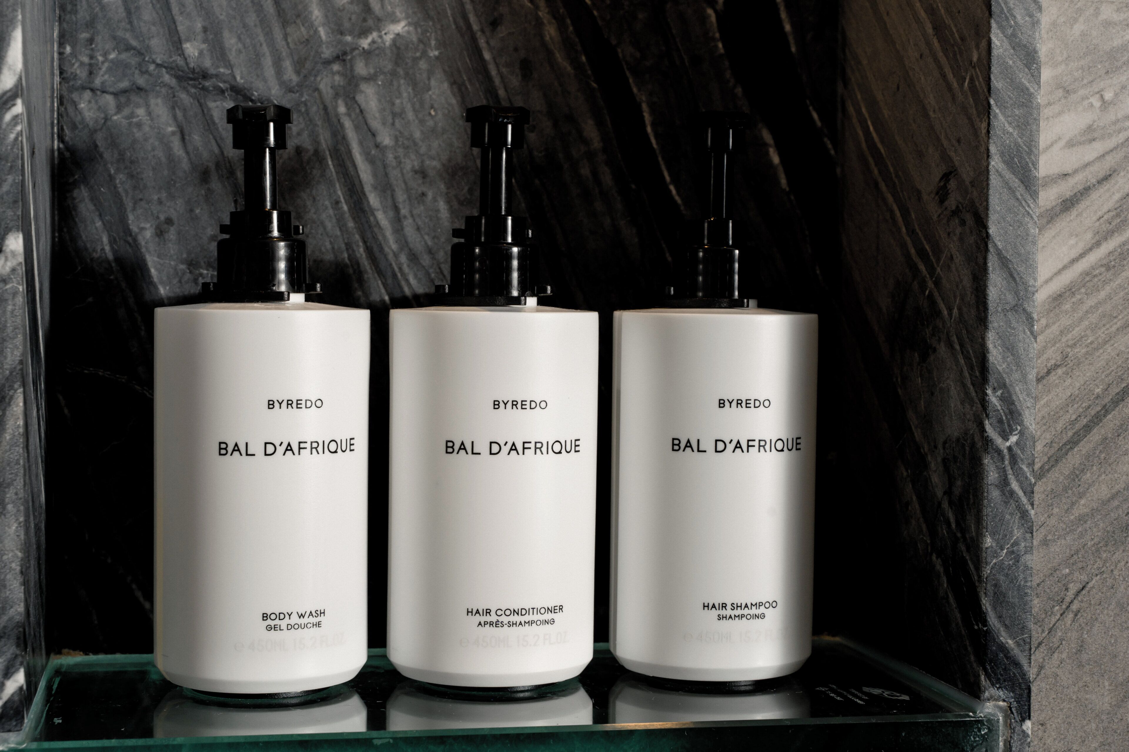 Three white bottles of BYREDO BAL D'AFRIQUE on a reflective surface.