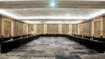 Une grande salle de conférence avec une longue table, de nombreuses chaises et un sol recouvert de moquette.