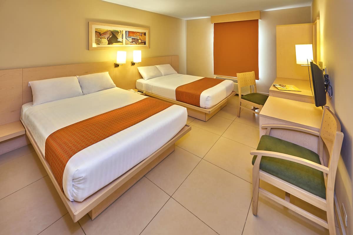 Ein Hotelzimmer mit zwei Betten, einem Schreibtisch, einem Stuhl und einem Fernseher.