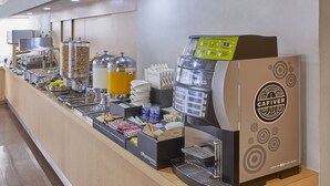 Una estación de café de autoservicio con una máquina de café, dispensadores y diversas opciones de comida.