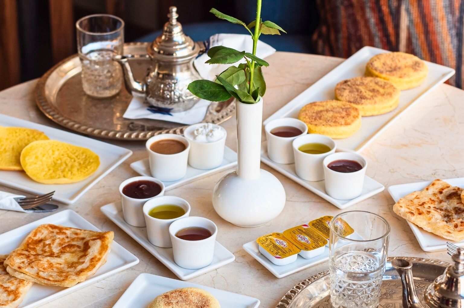 Una mesa dispuesta con diferentes platos, incluyendo pan plano, pasteles y pequeñas salsas.