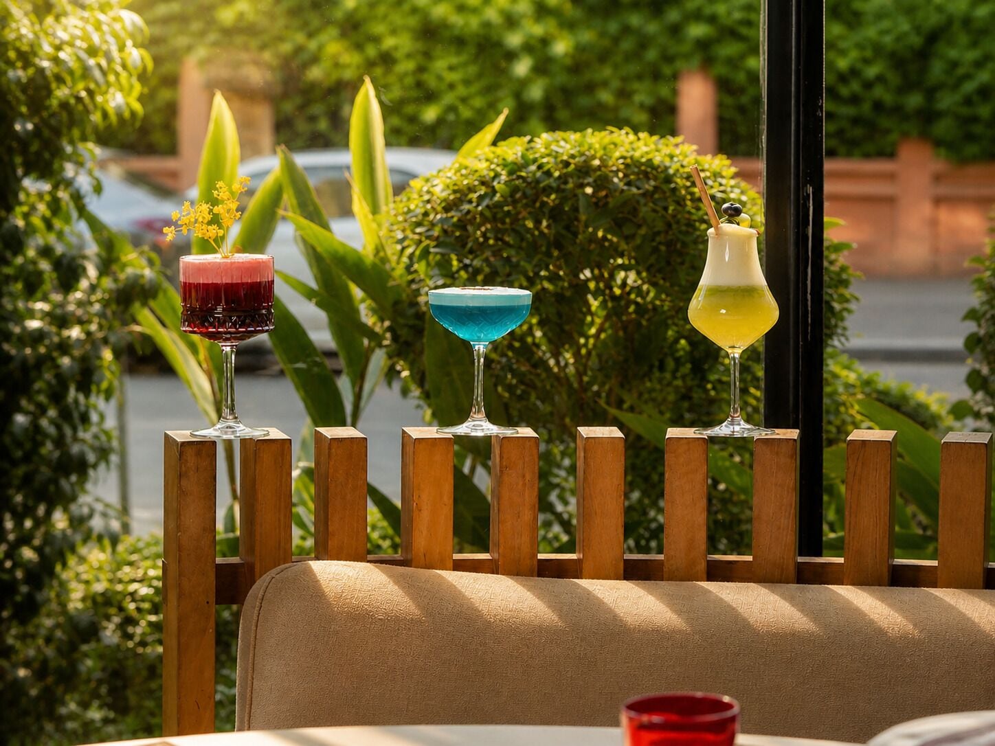 A row of wooden stools with three glasses of different colored drinks on top.