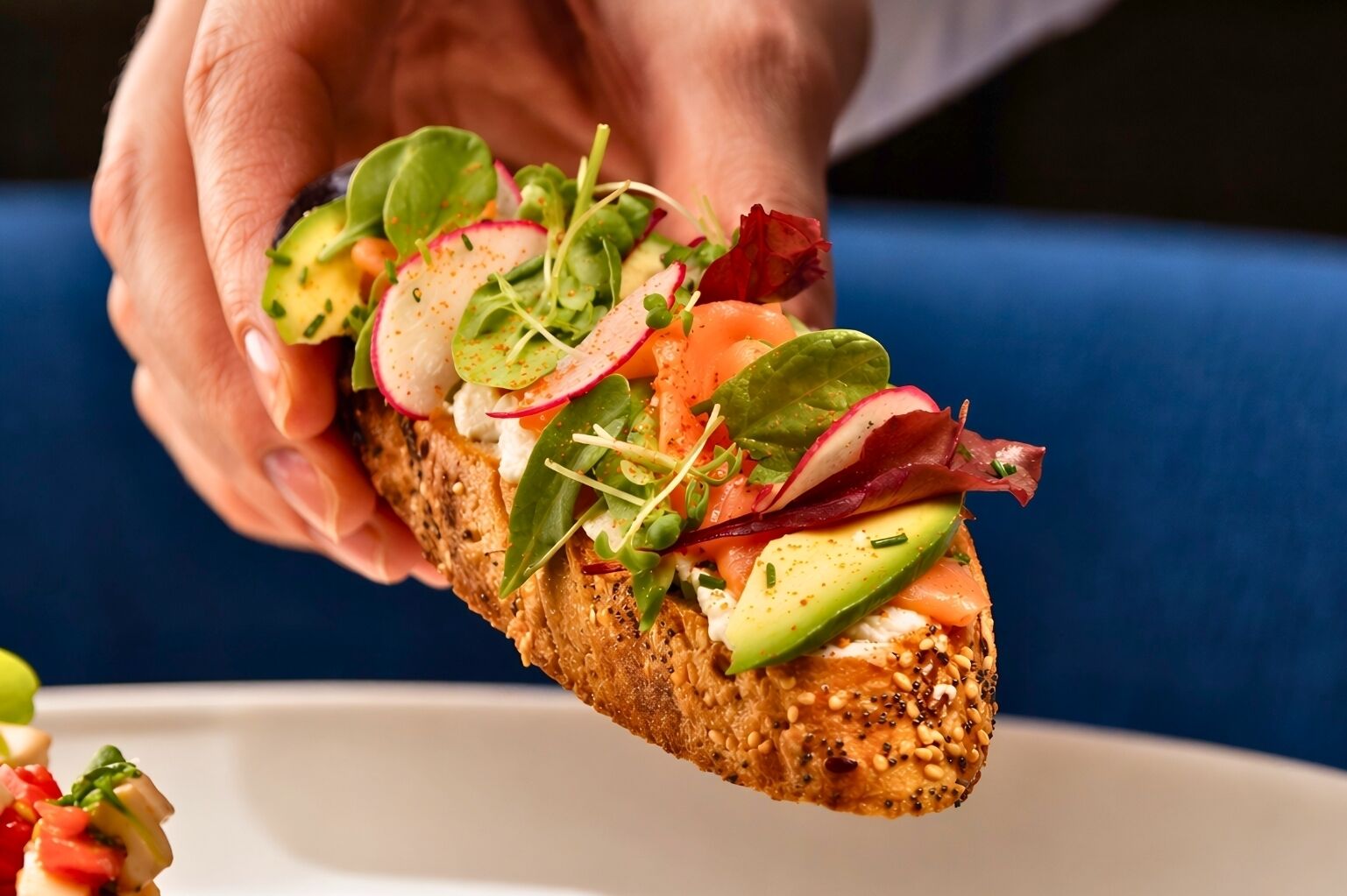 A hand holding a sandwich with various toppings.