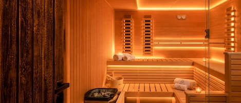 Eine Sauna mit Holzbänken, einer Holztür und einem Wandofen.