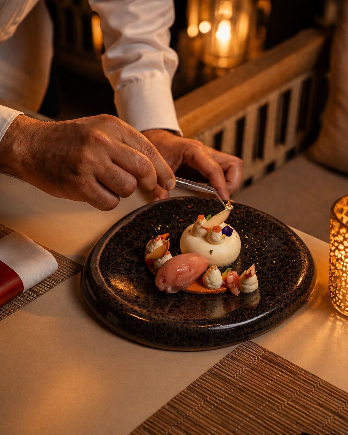 Una persona sirviendo comida en un plato oscuro con una servilleta de tela blanca.