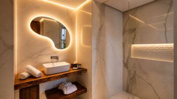 A modern bathroom with a marble sink, wooden vanity, and a glass shower enclosure.