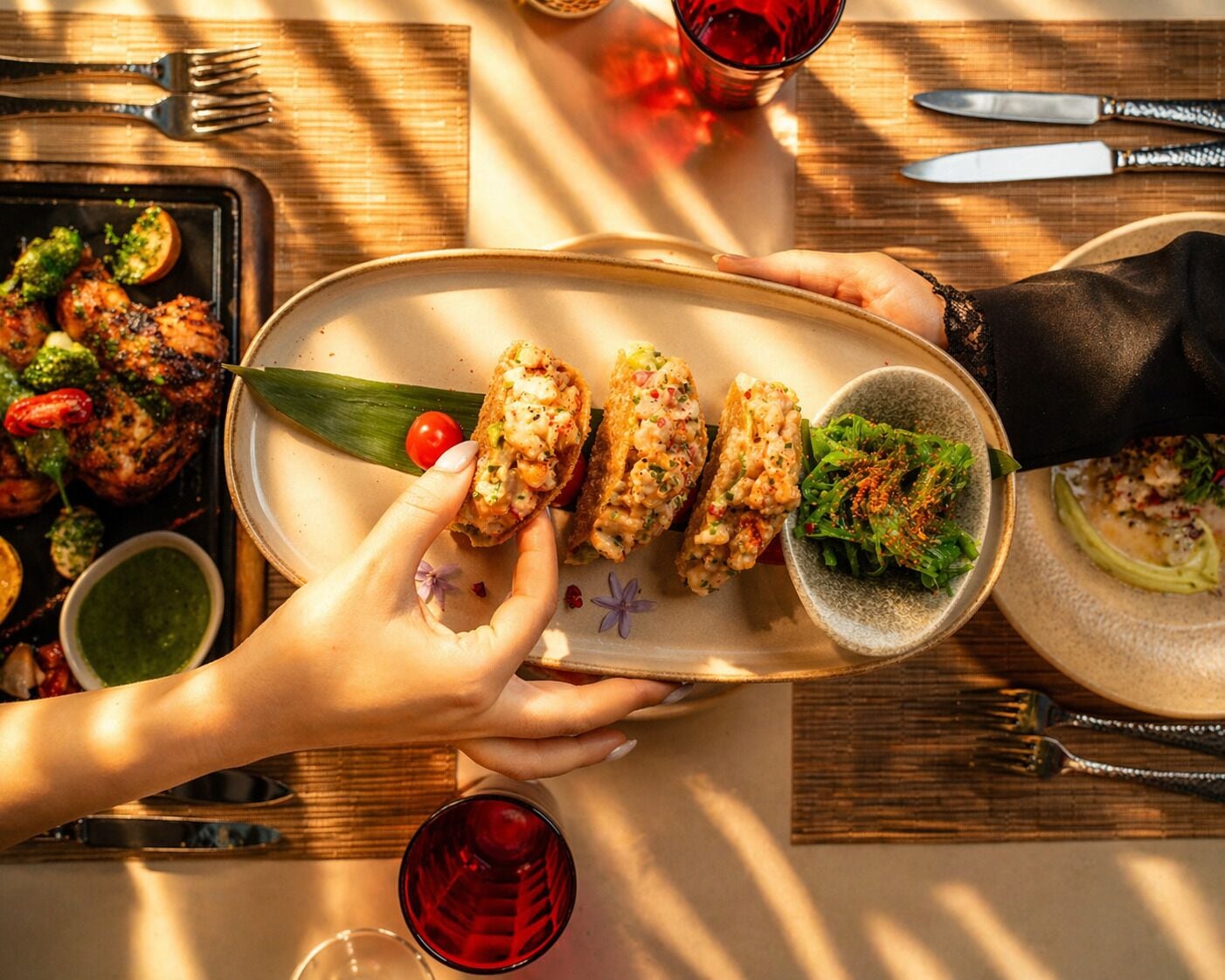 Une table à manger avec une assiette de nourriture, un saladier rempli de salade et un verre de vin rouge.