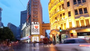 A city street with a prominent building featuring a large illuminated sign. - Seventh Heaven Hotel (Shanghai)