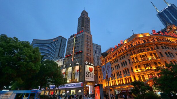 A cityscape with a prominent building featuring a large 'I ♥ SH' sign, surrounded by other illuminated buildings and a clear sky. - Seventh Heaven Hotel (Shanghai)