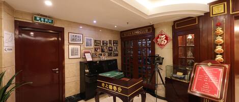 A lobby with a wooden reception desk, framed pictures on the wall, a piano, and a sign for the Seven King Club.