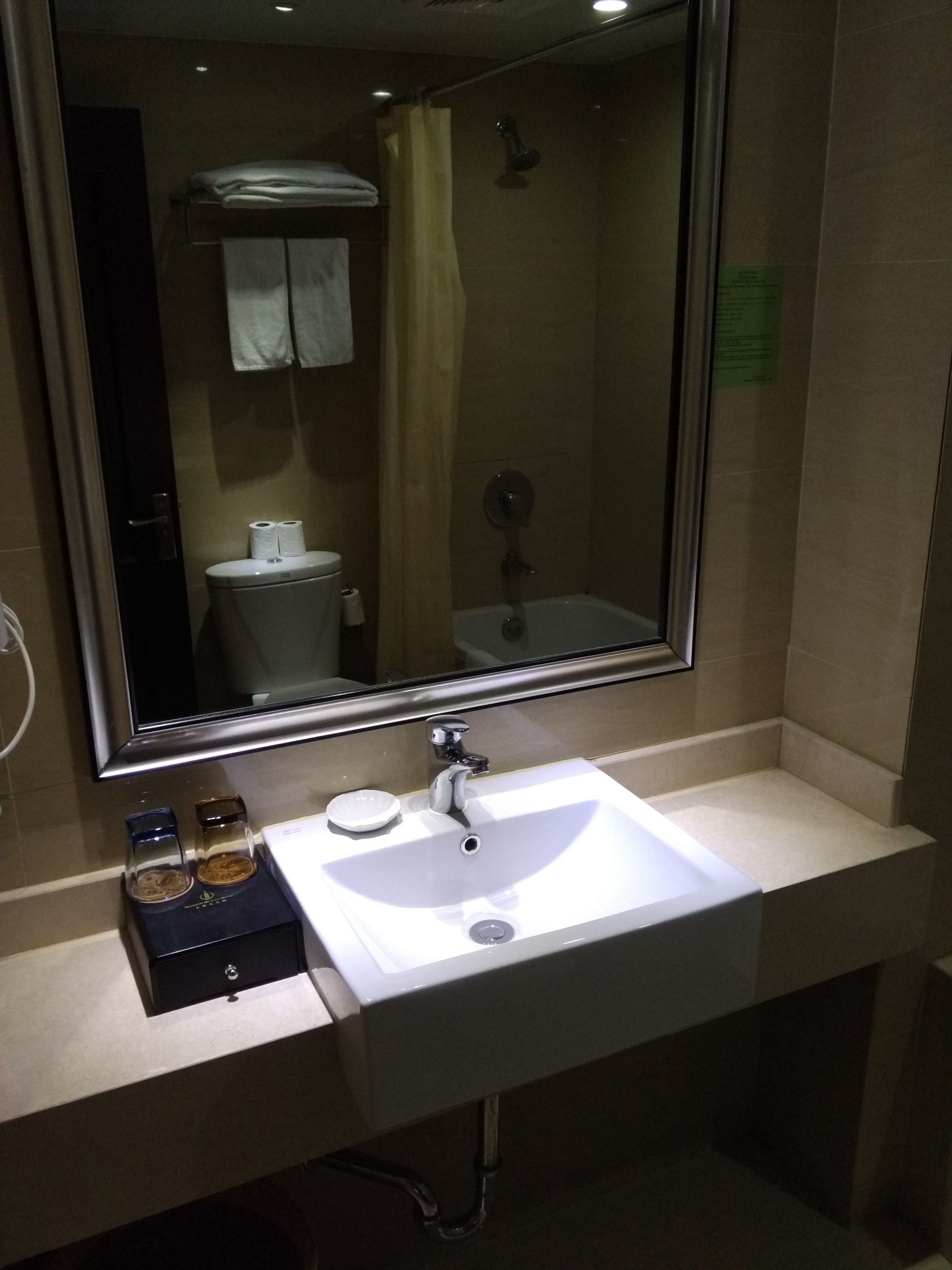 Un baño con lavamanos blanco, un espejo y zona de ducha.