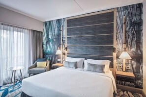 A modern hotel room with a large bed, a chair, a small table, and a wall with a unique design. - Le Suffren Hotel & Marina (Port Louis)
