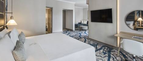 A hotel room with a large bed, a desk, a TV, and a mirror.