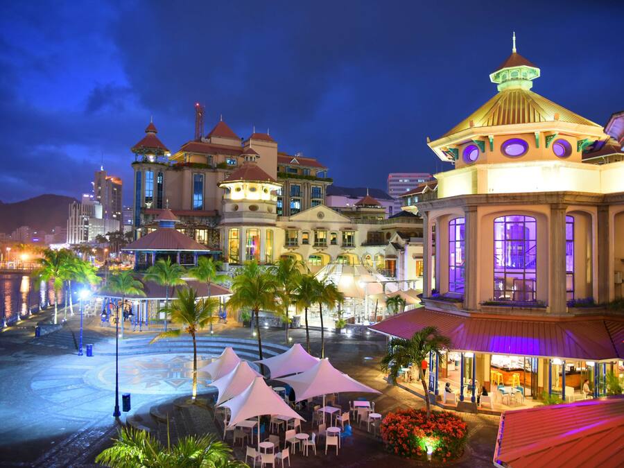 A waterfront hotel with multiple buildings, outdoor seating areas, and a well-lit plaza.