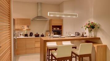 Une cuisine moderne avec des meubles en bois, un îlot central doté de sièges et un four à micro-ondes encastré.
