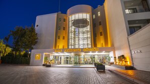 A modern building with a curved facade, large glass windows, and a sign reading "FAME RESIDENCE GÖYNÜK". - Fame Residence Göynük - All Inclusive (Kemer)