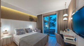 A modern hotel room with a bed, desk, and a large TV. - Fame Residence Göynük - All Inclusive (Kemer)