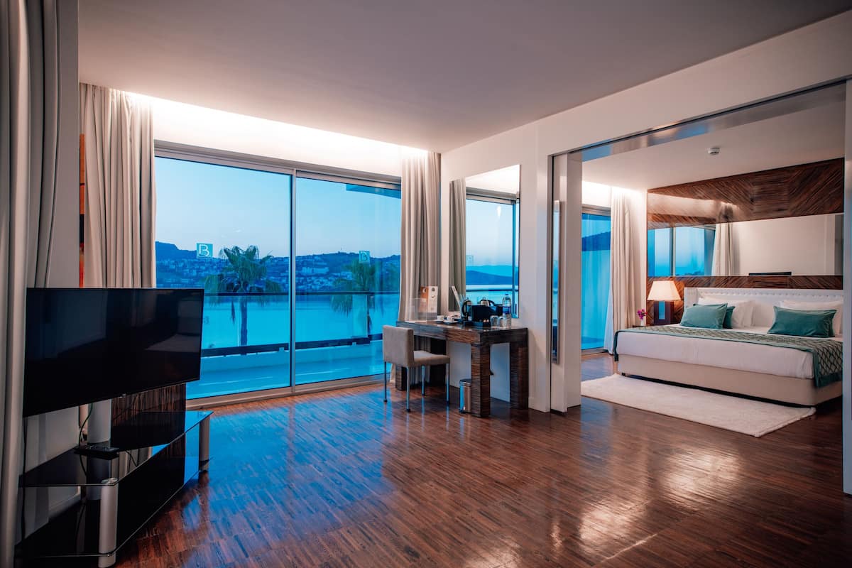 Een moderne hotelkamer met een groot balkon, een flatscreen televisie, een bureau en een comfortabel bed.