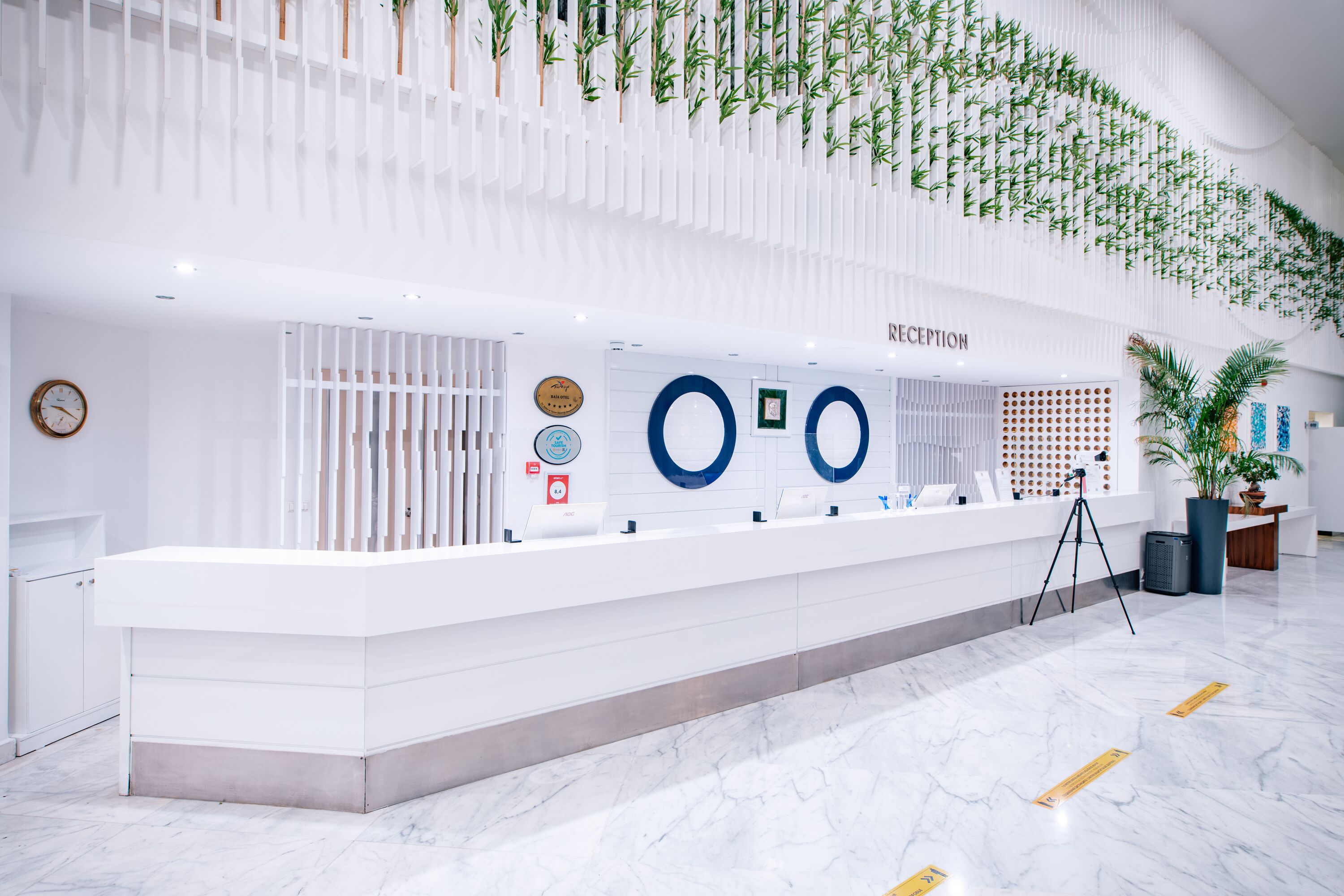 A reception area with a white reception desk, a clock, and a wall-mounted sign indicating the reception.
