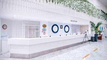 A reception area with a white reception desk, a clock, and a wall-mounted sign indicating the reception.