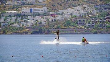 Zona costera con edificios, una persona practicando wakeboard y un jet ski.